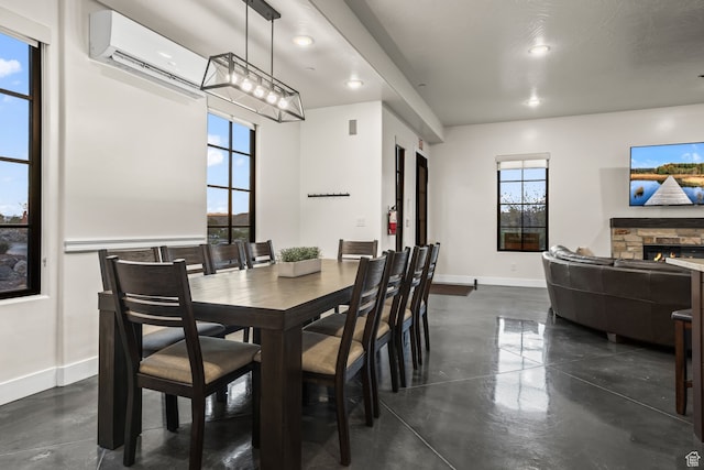 dining area featuring a wall mounted AC, baseboards, recessed lighting, a fireplace, and finished concrete floors