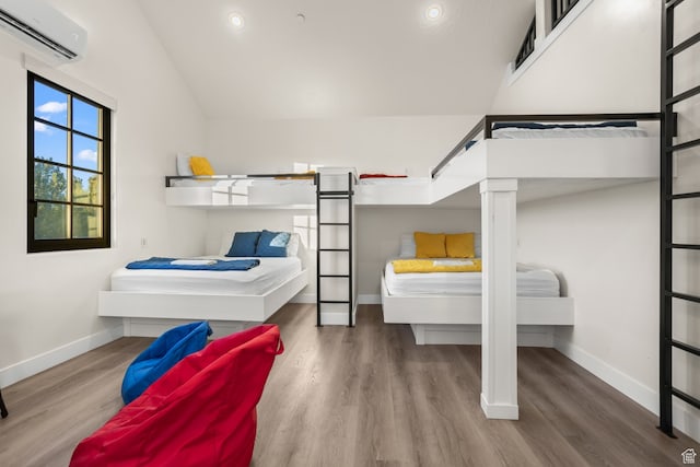 bedroom featuring baseboards, wood finished floors, and a wall unit AC