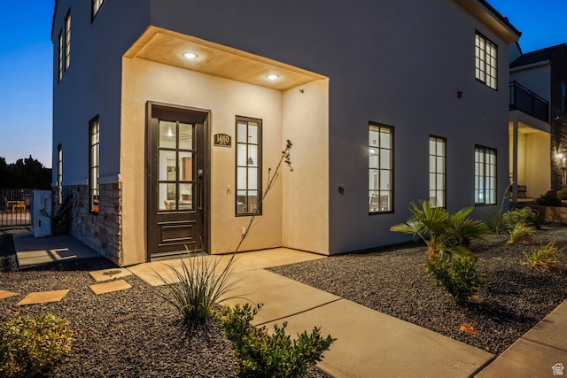 view of exterior entry featuring stucco siding and stone siding
