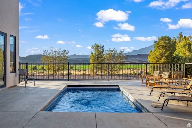 view of swimming pool featuring a mountain view, a fenced in pool, and a patio