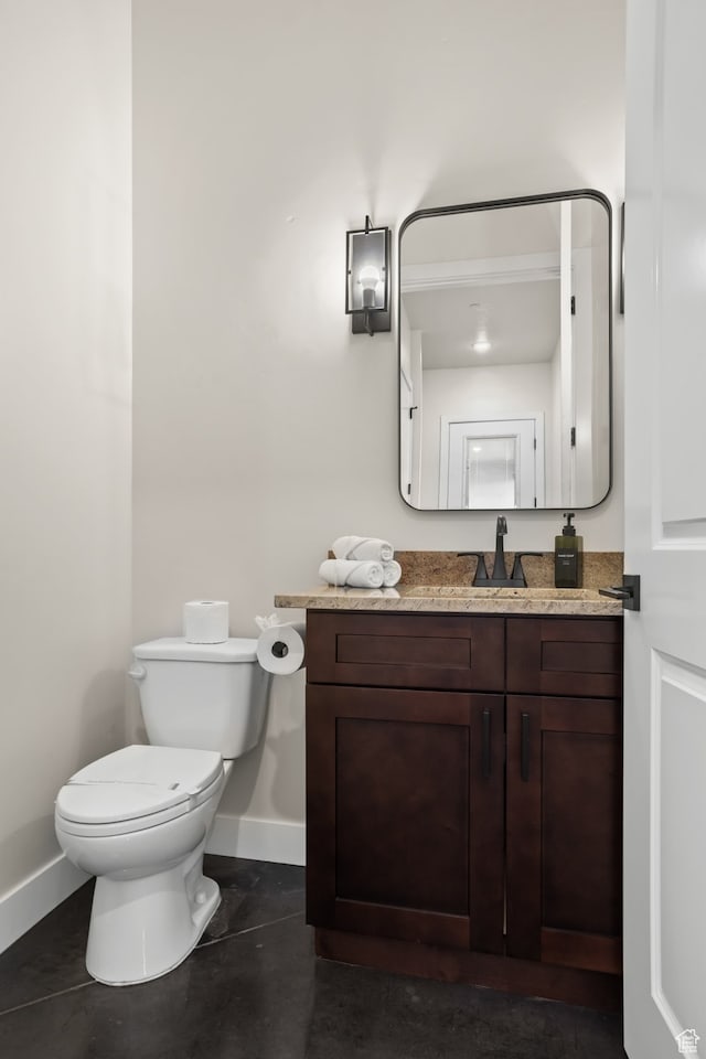 half bathroom with vanity, baseboards, and toilet