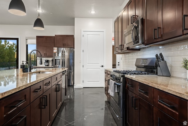 kitchen featuring tasteful backsplash, hanging light fixtures, a sink, stainless steel appliances, and light stone counters