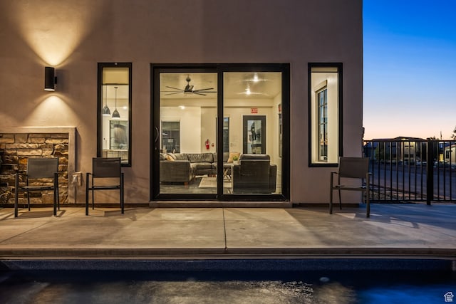 exterior entry at dusk with a patio area, an outdoor living space, fence, and stucco siding