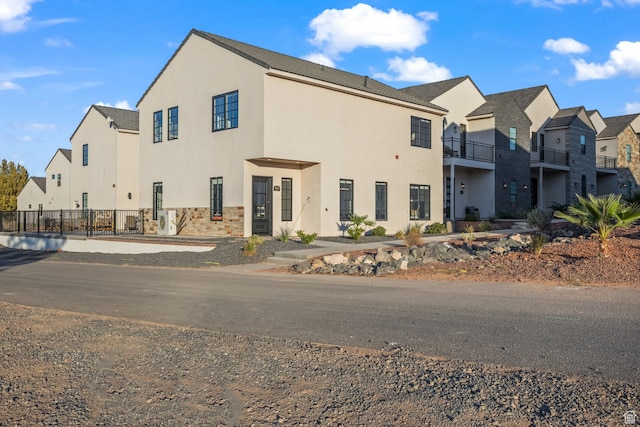 view of front facade with stucco siding, stone siding, and fence