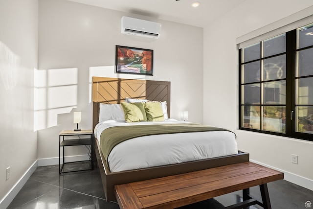 bedroom featuring finished concrete floors, baseboards, and a wall unit AC