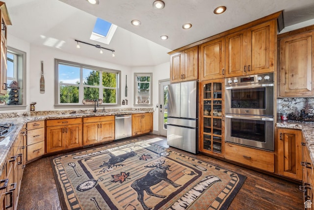 8938 N Canyon Wash Dr, Eagle Mountain, UT 84005 - kitchen with light stone counters, recessed lighting, appliances with stainless steel finishes, brown cabinets, and dark wood finished floors