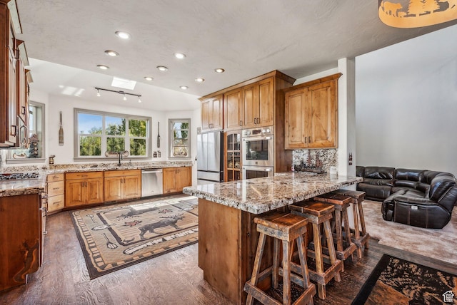 8938 N Canyon Wash Dr, Eagle Mountain, UT 84005 - kitchen featuring stainless steel appliances, tasteful backsplash, wood finished floors, light stone countertops, and a peninsula