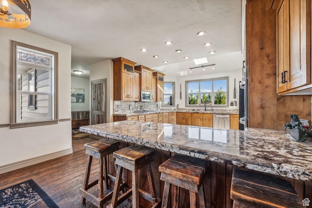 8938 N Canyon Wash Dr, Eagle Mountain, UT 84005 - kitchen with a kitchen breakfast bar, a peninsula, appliances with stainless steel finishes, and brown cabinets