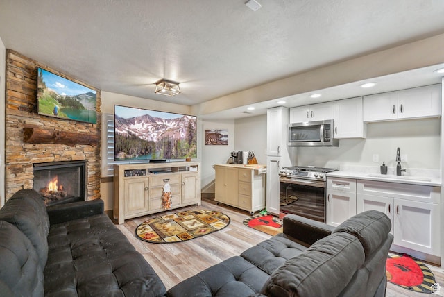8938 N Canyon Wash Dr, Eagle Mountain, UT 84005 - living room with light wood-style floors, a fireplace, and a textured ceiling