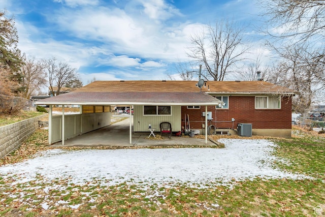 10551 Violet Dr, Sandy, UT 84094 - snow covered rear of property featuring an attached carport, brick siding, and a shingled roof