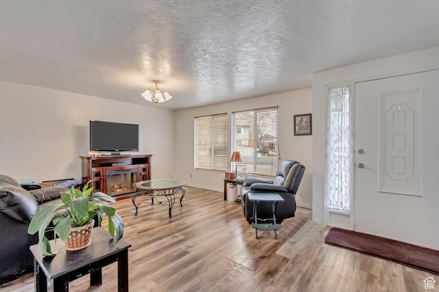 10551 Violet Dr, Sandy, UT 84094 - living room featuring a chandelier, light wood-type flooring, and a textured ceiling