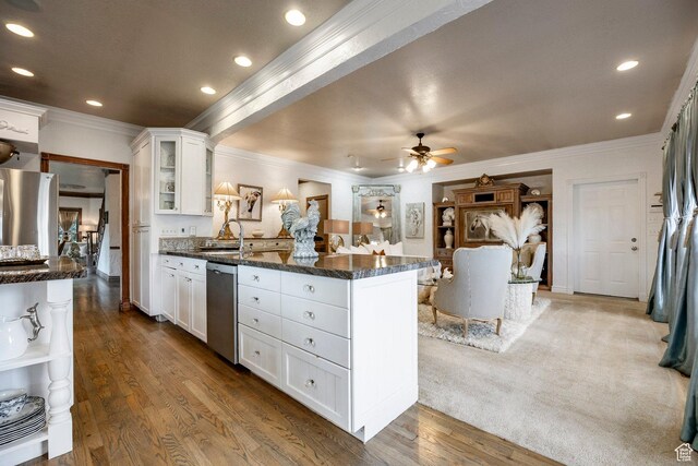 kitchen with white cabinets, appliances with stainless steel finishes, a sink, a peninsula, and ornamental molding