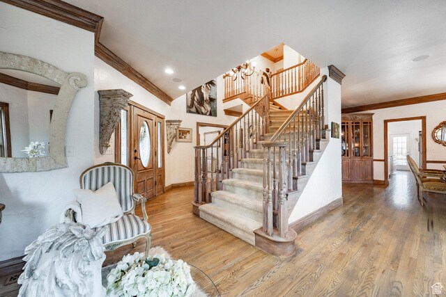 stairway with crown molding, an inviting chandelier, lofted ceiling, wood finished floors, and baseboards