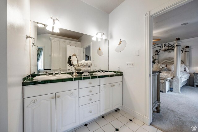 bathroom with a sink, baseboards, tile patterned flooring, and double vanity