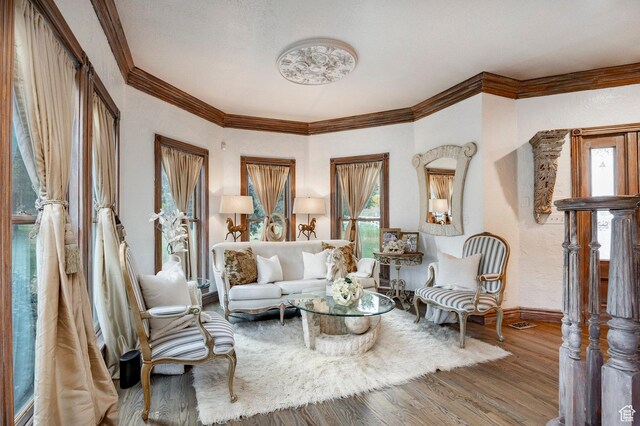 sitting room featuring baseboards, ornamental molding, a textured wall, and wood finished floors