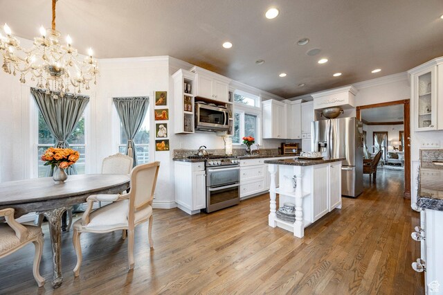 kitchen with crown molding, open shelves, appliances with stainless steel finishes, a notable chandelier, and white cabinetry