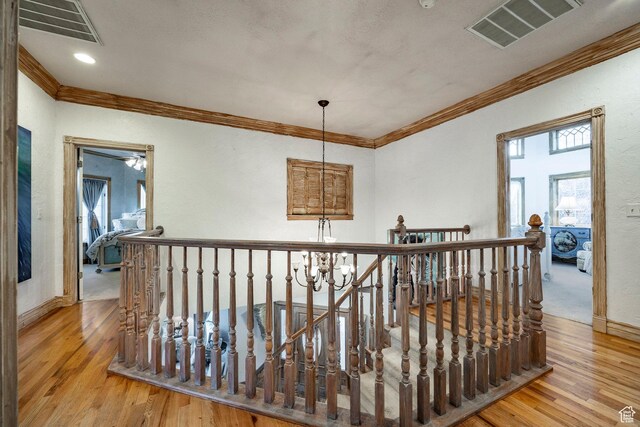hallway featuring crown molding, an upstairs landing, wood finished floors, and visible vents