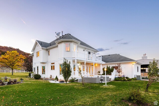 rear view of property featuring an outdoor living space, a patio area, fence, a balcony, and a yard