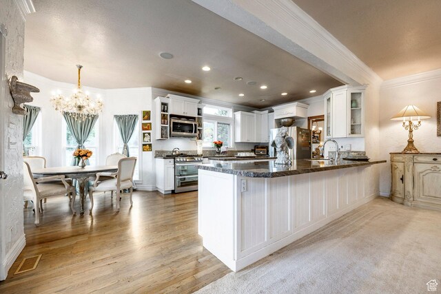 kitchen with crown molding, open shelves, a peninsula, an inviting chandelier, and stainless steel appliances