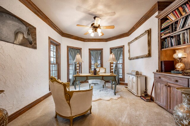 office area with a ceiling fan, light colored carpet, crown molding, baseboards, and a textured wall