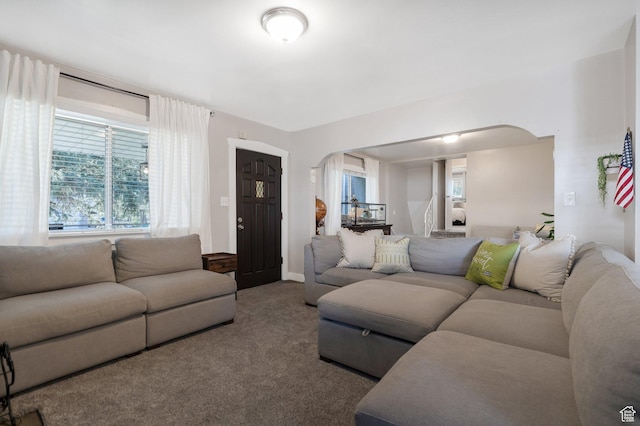 carpeted living area featuring arched walkways