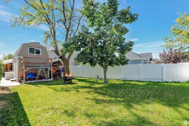 view of yard with an outbuilding, a storage shed, a fenced backyard, and an outdoor fire pit
