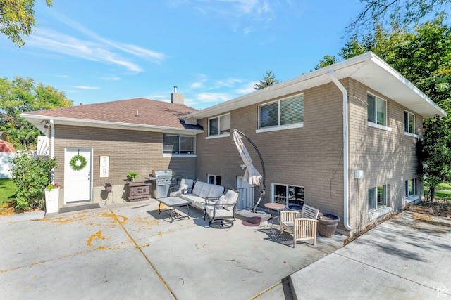 back of property featuring a chimney, brick siding, a patio, and an outdoor living space