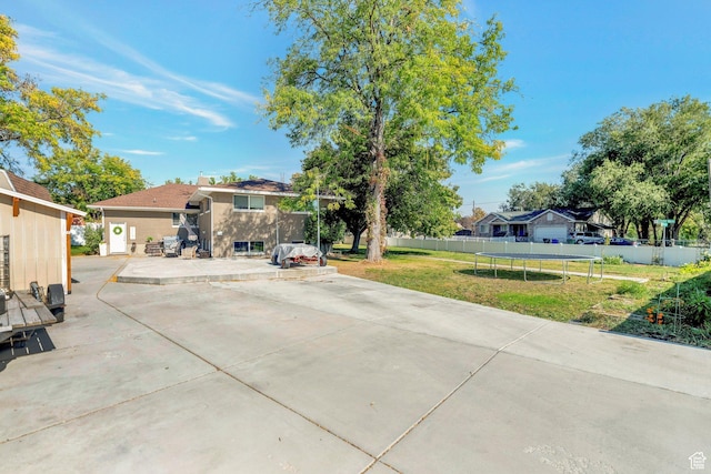 view of front facade featuring a patio, a residential view, a trampoline, a front yard, and fence