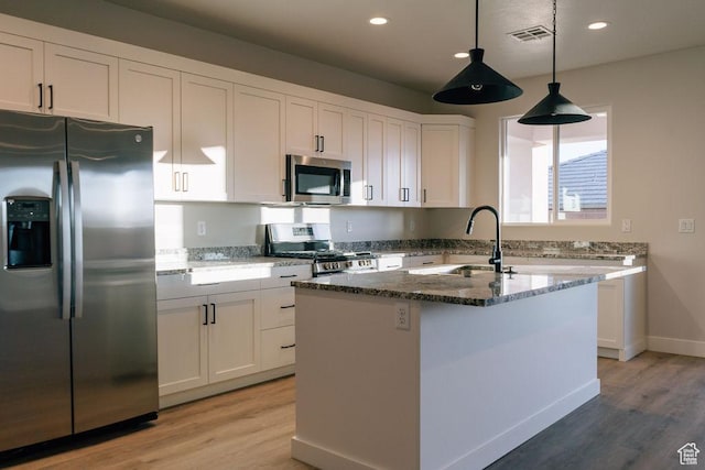 803 W 430 N, Hurricane, UT 84737 - kitchen featuring appliances with stainless steel finishes, a sink, dark stone countertops, light wood-style flooring, and white cabinetry