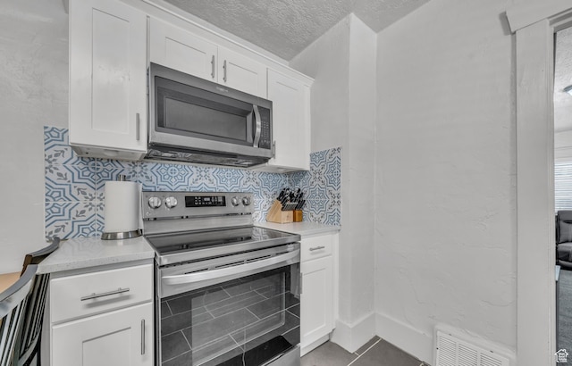 kitchen featuring white cabinetry, tasteful backsplash, stainless steel appliances, and a textured ceiling