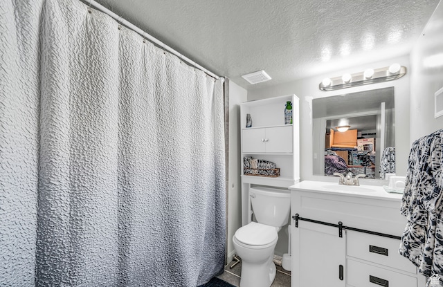 bathroom with vanity, toilet, tile patterned floors, and a textured ceiling
