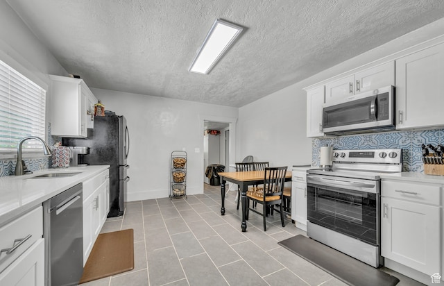 kitchen featuring appliances with stainless steel finishes, sink, a textured ceiling, white cabinetry, and light tile patterned floors