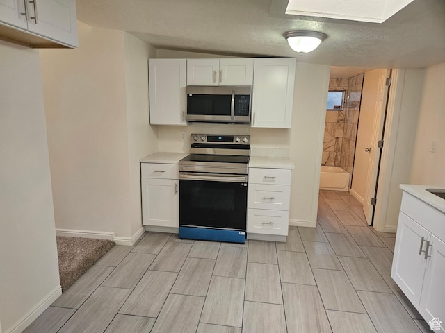 551 E Commonwealth Ave, Salt Lake City, UT 84106 - kitchen with wood tiled floor, stainless steel appliances, light countertops, baseboards, and white cabinetry
