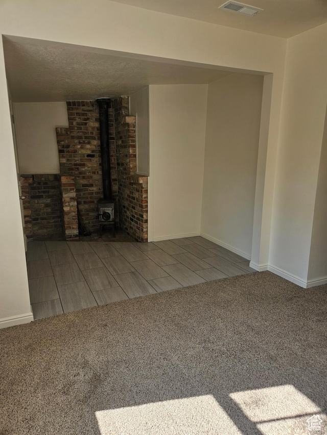 551 E Commonwealth Ave, Salt Lake City, UT 84106 - basement with carpet flooring, baseboards, a wood stove, and visible vents