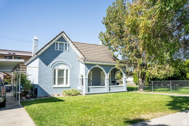 view of front of home with a front lawn, stucco siding, a tile roof, and fence