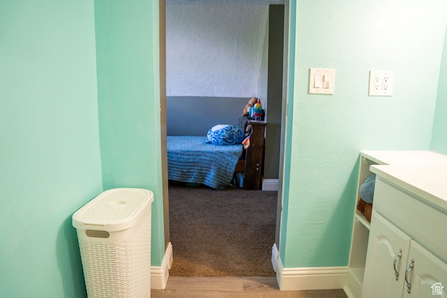 bedroom featuring baseboards, a textured wall, and wood finished floors