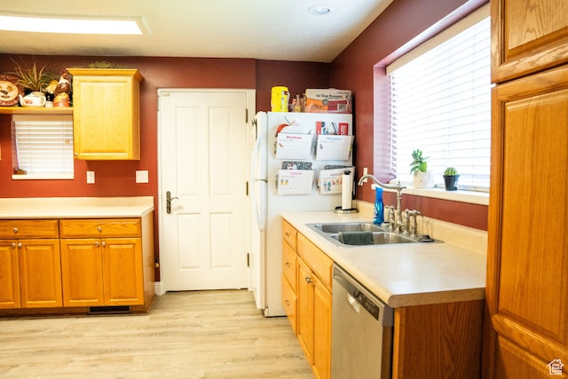 kitchen with stainless steel dishwasher, a sink, light countertops, freestanding refrigerator, and light wood-style floors
