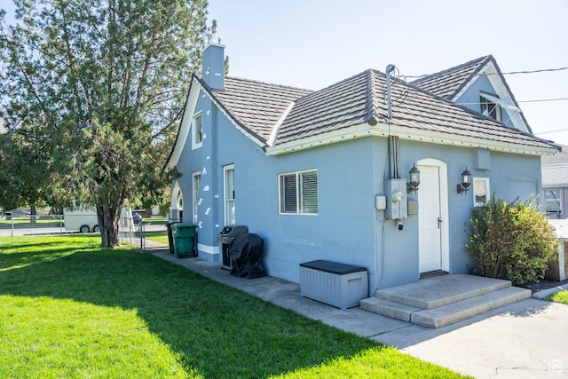 back of property featuring stucco siding, fence, a yard, and a chimney