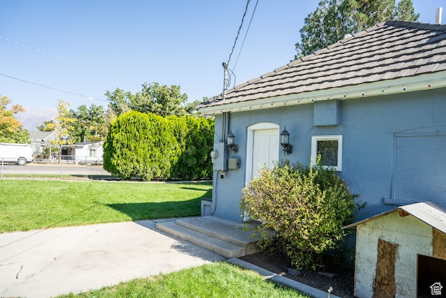 property entrance featuring a lawn, stucco siding, and a tiled roof