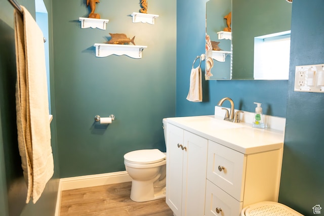 bathroom featuring baseboards, vanity, toilet, and wood finished floors