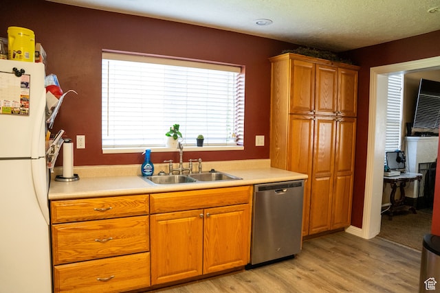 kitchen featuring dishwasher, a sink, light countertops, freestanding refrigerator, and light wood finished floors
