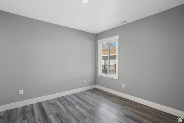 empty room with visible vents, baseboards, and dark wood-style flooring