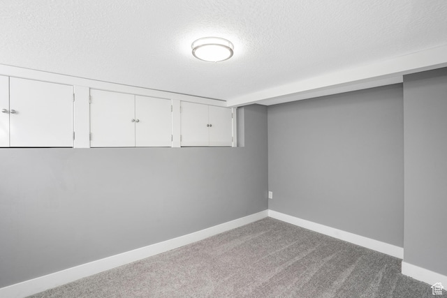 finished basement featuring baseboards, carpet floors, and a textured ceiling