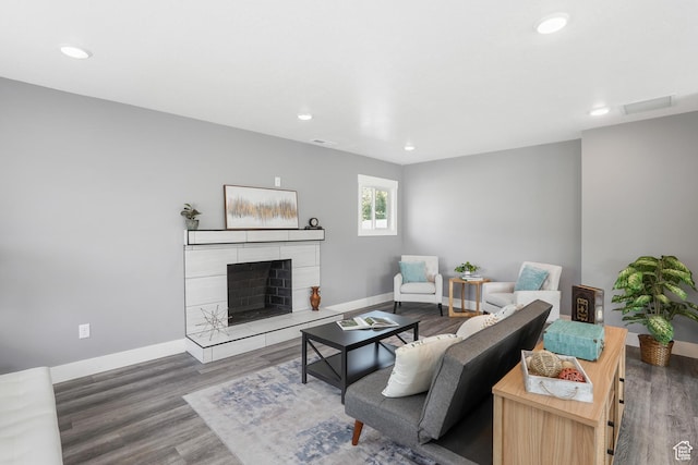 living area with a tiled fireplace, wood finished floors, and recessed lighting