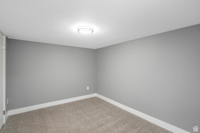unfurnished room with carpet, a textured ceiling, and baseboards