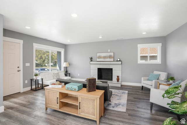 living room with baseboards, a tiled fireplace, and wood finished floors