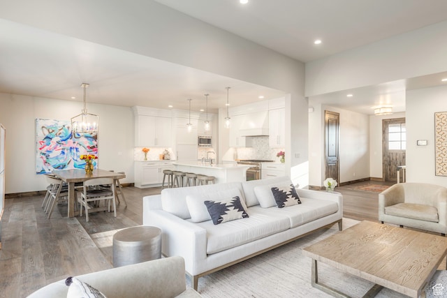 living room with sink, a notable chandelier, and hardwood / wood-style flooring