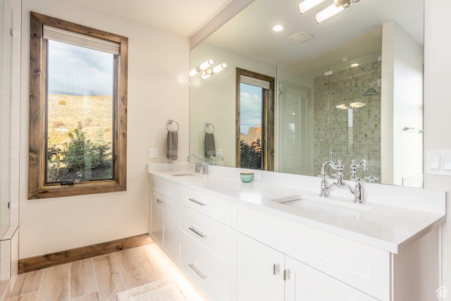 bathroom featuring vanity, wood-type flooring, a tile shower, and a wealth of natural light