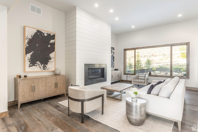 living room with dark hardwood / wood-style flooring, a large fireplace, and plenty of natural light