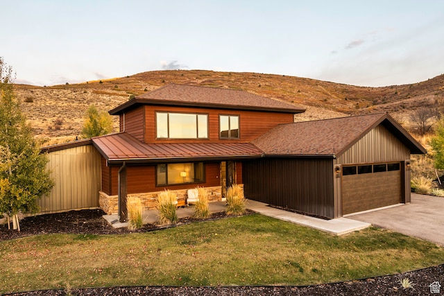 view of front of property with a mountain view, a front yard, and a garage